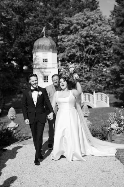 A wedding couple holding hands and celebrating after getting married