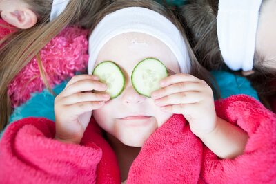 Young girl holding cucumbers while having an at home spa service provided by Feel Fabulous.