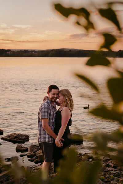 silhouette of engaged couple by the water at sunset