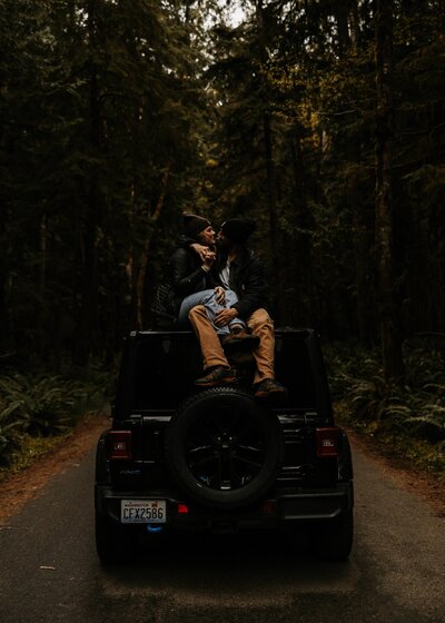 couple kiss each other atop their converted Jeep while on a camping trip to celebrate their engagement in Banff national park