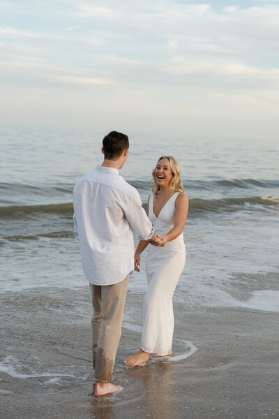 Couple laughing and holding hands at the beach by east coast photographer Shelby Ann Photos