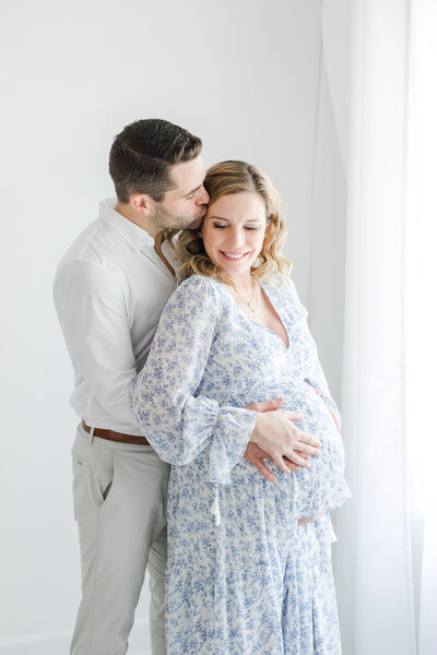 Husband embraces his pregnant wife from behind during maternity portrait session