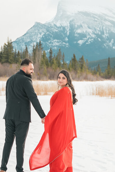 Man looking at fiancee during their winter engagement photo session in Banff