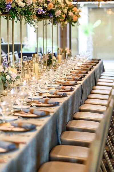 A long dining table with elegant place settings and floral arrangements, capturing the refined style of a luxury wedding reception by Socially Significant Events.