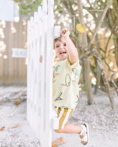 Little boy smiling climbing on a fence