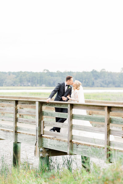 bride & groom kissing on dock at their oldfield club wedding