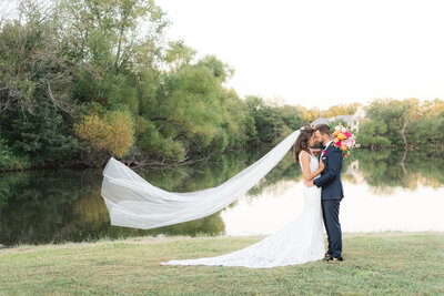 sunset wedding couple portrait with navy tuxedo and Pnina Tornai gown in front of lake