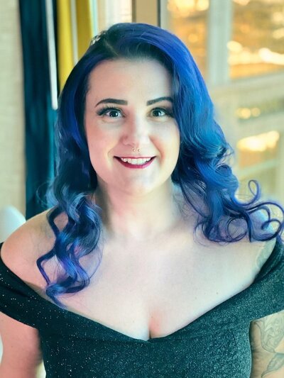 Nicole L. styled by Your Girl Friday LV with vivid navy blue waves and a sparkly off-the-shoulder dress, captured in glowing natural light for her event.