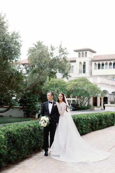 Bride sitting on tree branch in Forsyth Park smiling at groom.