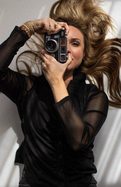 Photographer woman lying on the ground holding a camera up to her eye