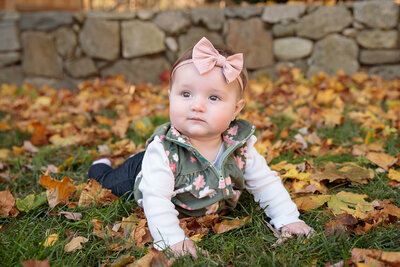 Baby boy sits in field of yellow flowers smiling at camera