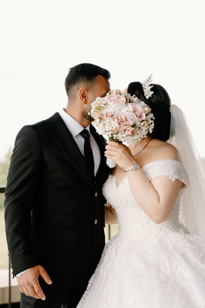 couple kissing behind bouquet