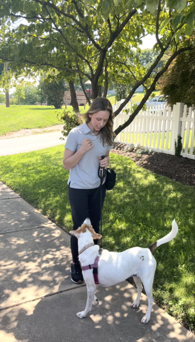 Dog trainer Michelle Pennarola outside with a brown and white dog