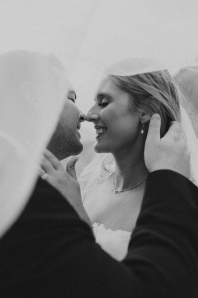 couple holding onto each other during montana wedding photos under brides veil