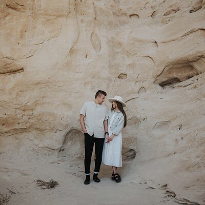 couple holding hands and smiling at each other in the desert.