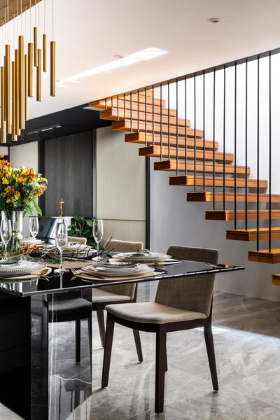 Dining area with wooden stairs and storage compartment in the background, with two lights above.