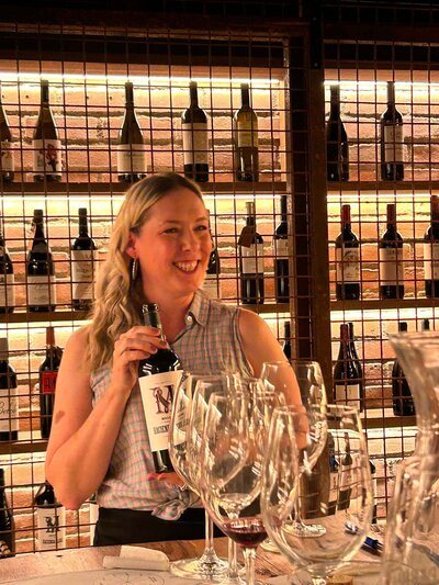 Owner of Wine Guide Madrid Maria Cristina Barrero holding a wine bottle and smiling.