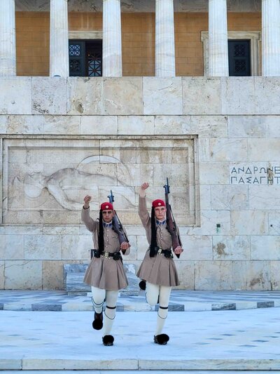 Evzones (guards) performing ceremonial guard march at Syntagma Square in Athens, Greece, with marble columns and classical reliefs in background ©Stephanie Dosch | theViatrix Luxury Travel