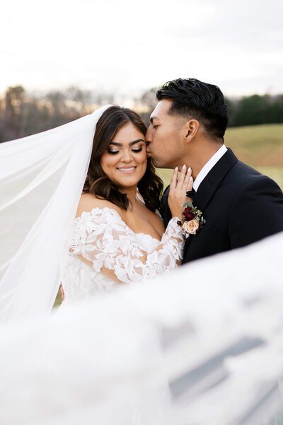 bride holding her dress out to the side as she dances with her groom is a field full of horses at a Charlottesville wedding venues