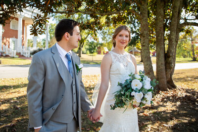 Newly weds holding hands in front of Heritage House.