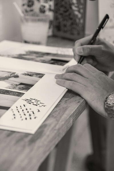 Black and white photo of guest signing Arizona wedding guestbook.