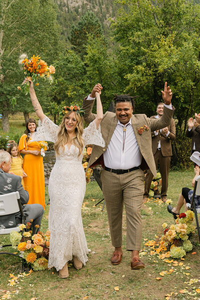 Joyful wedding exit after a Colorado outdoor ceremony at Venue On The Rocks in Estes Park
