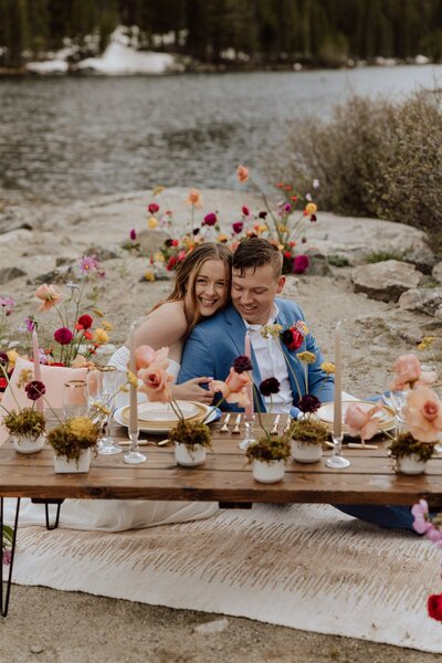 bride and groom sitting at a low table in front of a mountain