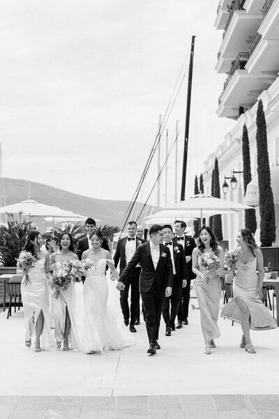 Bride, groom and wedding party walking joyfully together in black and white, destination wedding photo by Toronto photographer