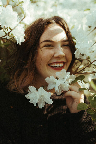 portrait of photographer holding white flowers and smiling