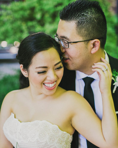Groom stands behind Bride as she smiles looking to her left