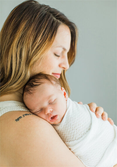 Newborn portrait of baby’s head resting on mother’s shoulder taken by Nashville Newborn Photographer