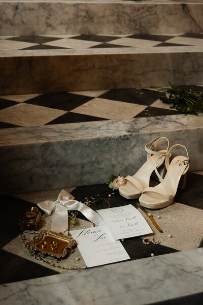 Flat lay of elegant wedding invitations styled beside a classic black-and-white checkered staircase at a Kentucky wedding venue.