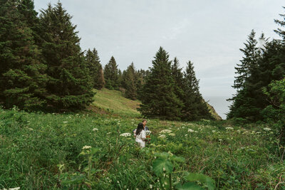 couple walks a hiking trail to a cliffside on the Oregon Coast during their destinations elopement.
