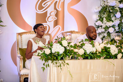 Newlyweds seated at a beautifully decorated sweetheart table during their luxury wedding reception.