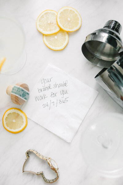 Lemons, gold watch, napkin notes on table with drink strainer
