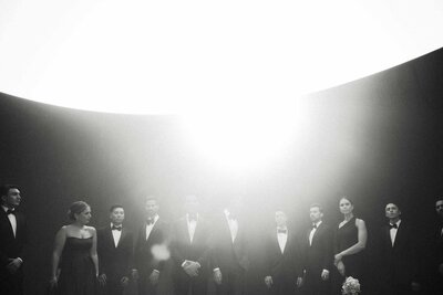 Dramatic black-and-white wedding party portrait under intense lighting