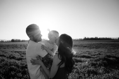 Family snuggles together during photography session in a clover field located in Corvallis, OR.