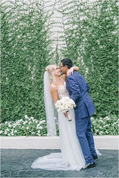 Bride and groom embrace in front of ivy covered wall at their wedding at the Bell Tower on 34th