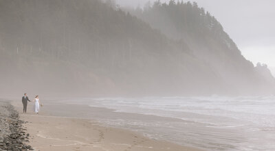 Couple holding hands and walking along the beach in Oregon.