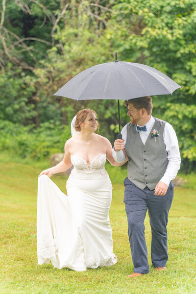 A groom is holding an umbrella while leading his new wife up a mountain in Virginia.