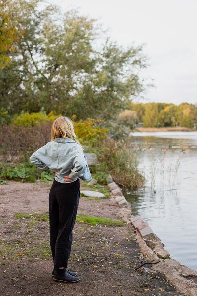 mielen paremminvoinnin ja kehomieliyhteyden valmentaja  katsoo rannalla kohti järvimaisemaa