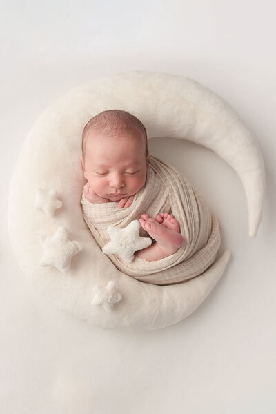 newborn baby boy swaddled wrapped in white fabric on a white blanket
