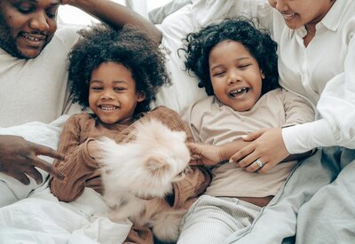 family of four laughing while laying on a bed
