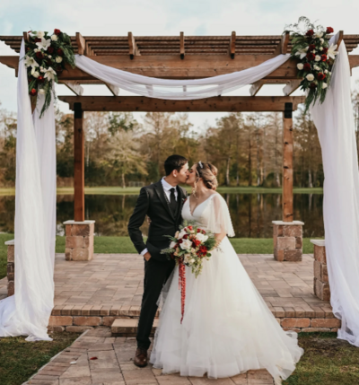 The sweetest couple poses under an archway at Cypress creek farmhouse, a barn wedding venues Orlando.