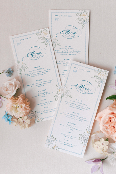 Custom floral menu and table number design for a pastel wedding at Moonlight Basin, featuring soft tones, elegant typography, and floral illustrations that tied into the couple’s stationery suite.