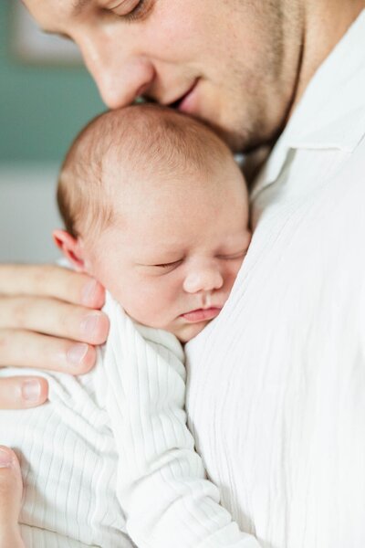 A newborn snuggled in a bed for an in home newborn photography session in Richmond