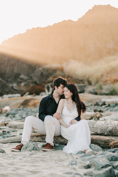 A couple cuddles on  driftwood at Seal Rock Beach State Park, OR. Photo by Jen White Photography