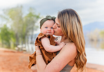 mom holding infant close and giving kiss on the cheek for by st george photographer sadie peterson photography