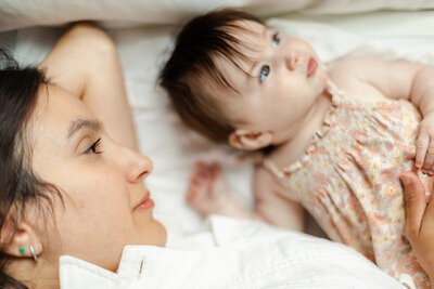at home milestone session in Pearland, Texas of baby looking away form mother while mother smiles and admires her baby girl