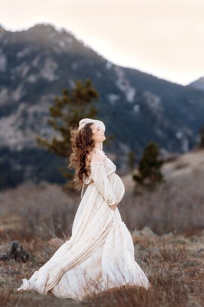 GORGEOUS PREGNANT MOM IN FLOWING MATERNITY DRESS AGAINST THE FLAT IRONS AT SOUTH MESA TRAULHEAD IN BOULDER AT SUNSET